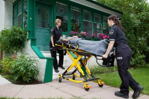 Two female paramedics remove an elderly woman from a home.