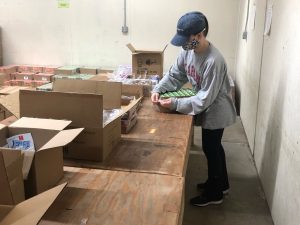 A white woman packs boxes inside a food pantry