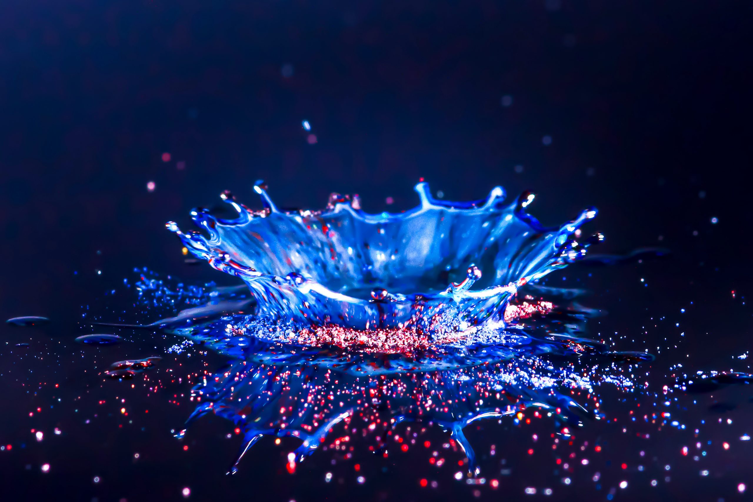 Drops of water colliding with powdered dye to create a multi coloured abstract droplet collision