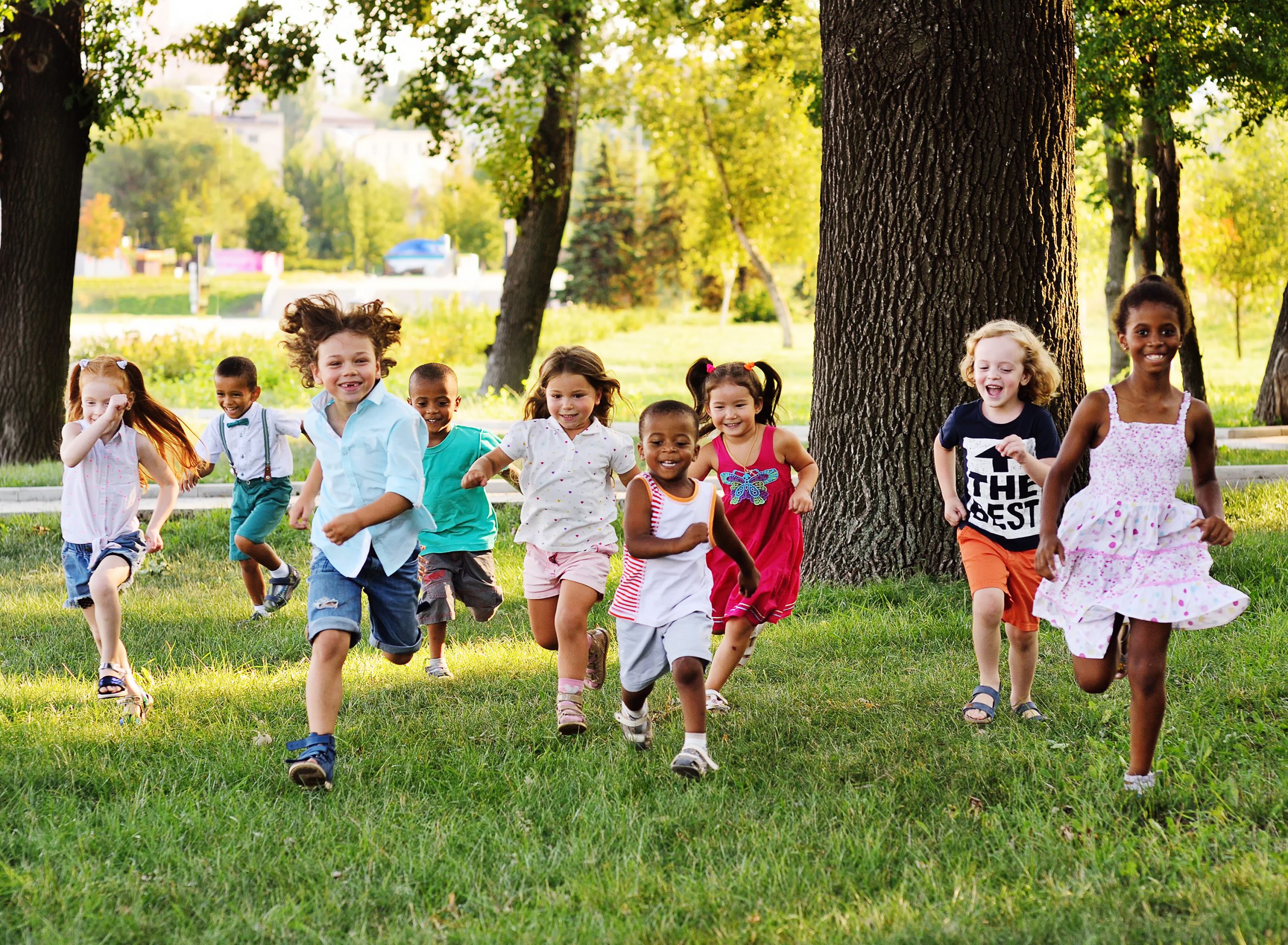 a group of preschoolers running on the grass in the Park.