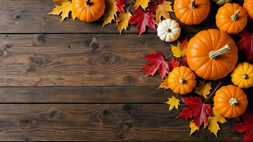 Autumn pumpkins and fall leaves on a rustic wood background.